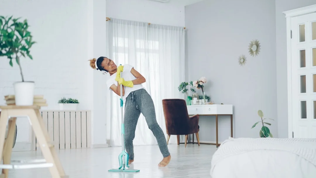 Asian couple having fun while cleaning their home, enhancing a cheerful atmosphere.